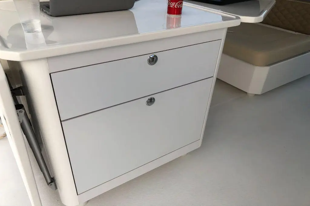 White drawer unit on a boat, featuring two drawers with chrome handles, and a can of Coca-Cola on the surface.